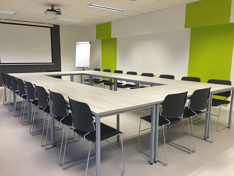 Large conference room with white walls and green accent colors.