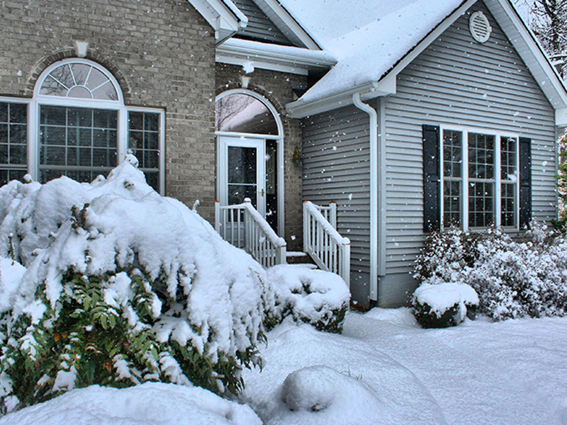 House with grey siding and brick in the snow.