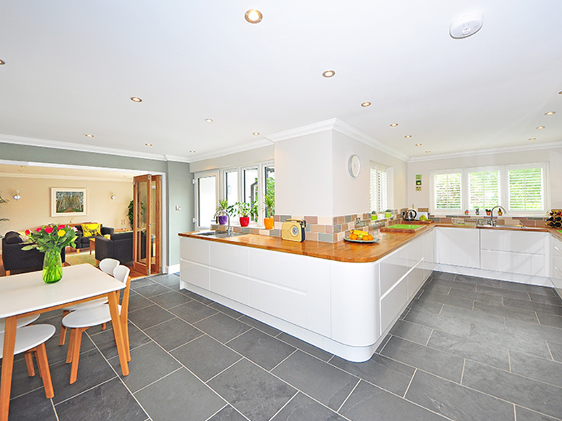 Interior painted kitchen with grey tile floor, wooden counters, white and green walls.