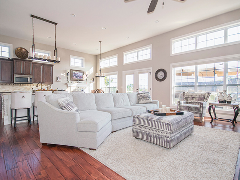 Interior painted living room with many windows, hardwood floors, a couch and grey painted walls.
